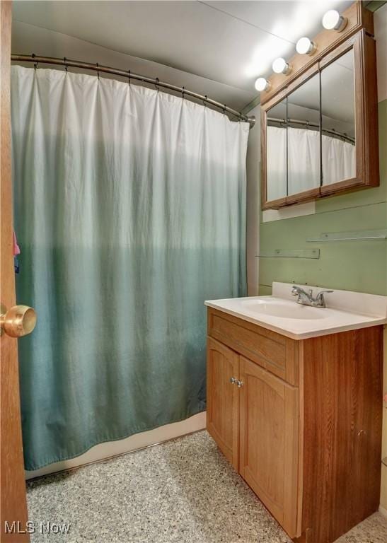 bathroom with a shower with curtain, speckled floor, and vanity