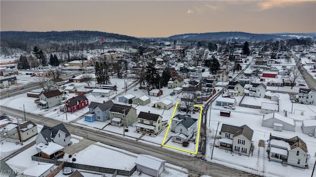 snowy aerial view featuring a residential view and a mountain view