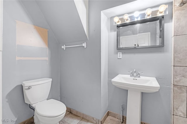 half bathroom featuring toilet, tile patterned flooring, baseboards, and a sink