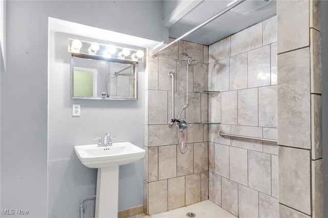 bathroom featuring a tile shower and a sink