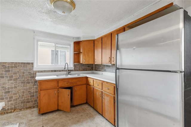 kitchen with freestanding refrigerator, light countertops, a textured ceiling, open shelves, and a sink