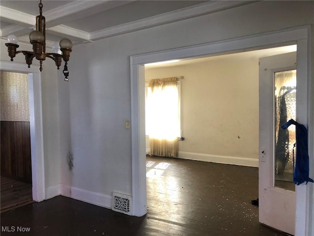 unfurnished dining area featuring a chandelier, coffered ceiling, wood finished floors, visible vents, and baseboards