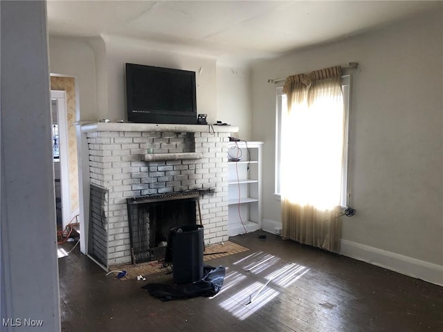 unfurnished living room with a fireplace, baseboards, and wood finished floors