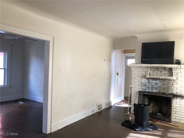 unfurnished living room with concrete floors, plenty of natural light, a fireplace, and baseboards