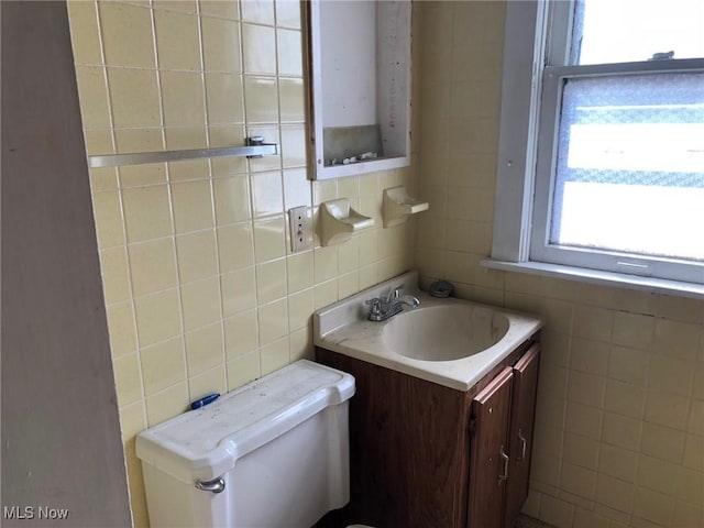 bathroom featuring toilet, tile walls, and vanity