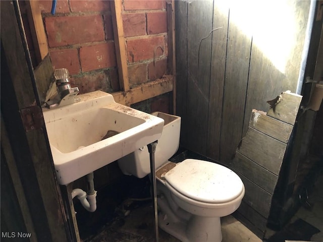 half bathroom with concrete block wall and toilet