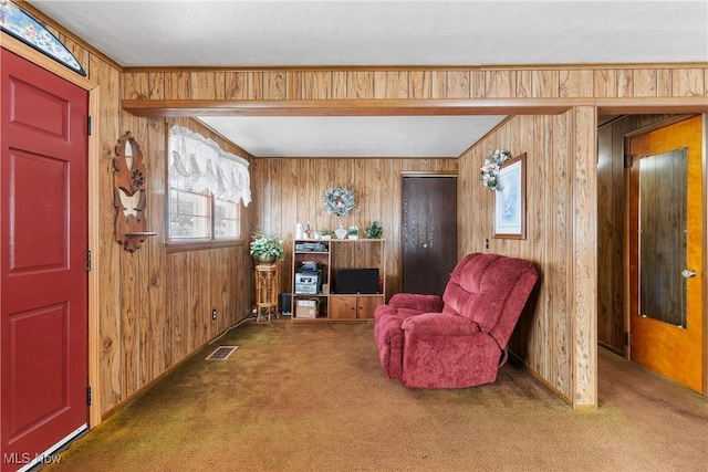 living area featuring wooden walls, carpet flooring, and visible vents