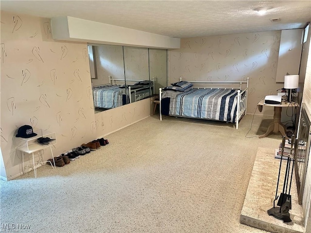 bedroom featuring visible vents, a textured ceiling, and wallpapered walls