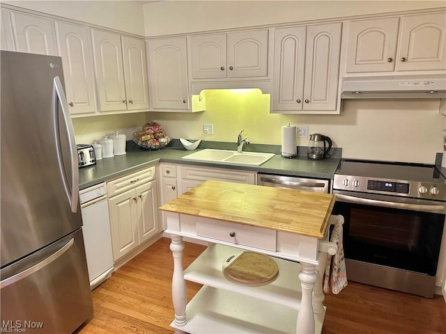 kitchen featuring white cabinets, light wood-style flooring, stainless steel appliances, under cabinet range hood, and a sink