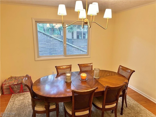 dining room with baseboards, ornamental molding, wood finished floors, a textured ceiling, and a chandelier