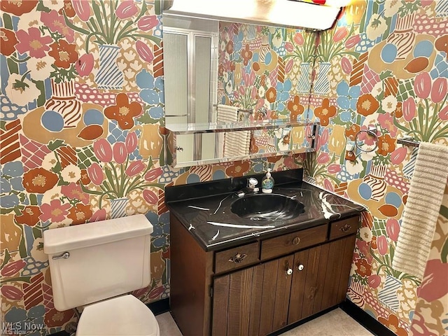 bathroom with vanity, toilet, and wallpapered walls