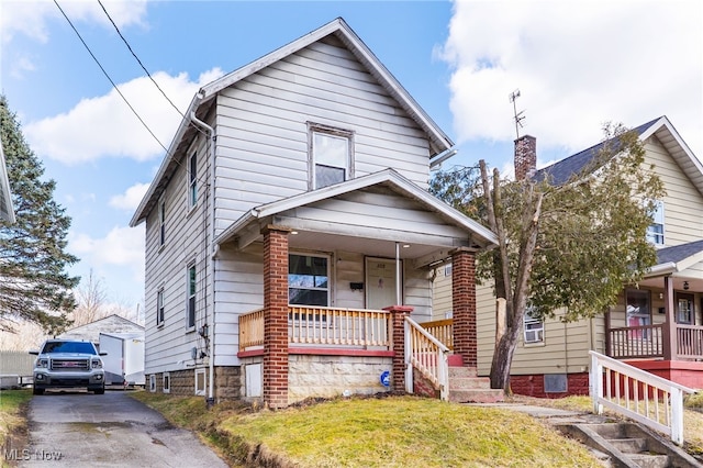 american foursquare style home with covered porch and a front lawn