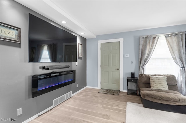 living area featuring baseboards, visible vents, a wealth of natural light, and wood finished floors