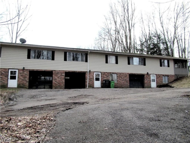 townhome / multi-family property featuring aphalt driveway, brick siding, and an attached garage