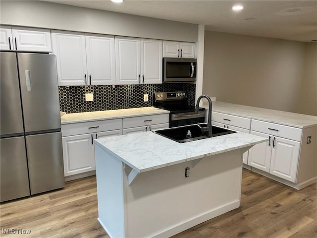 kitchen featuring light wood finished floors, appliances with stainless steel finishes, a sink, and white cabinets