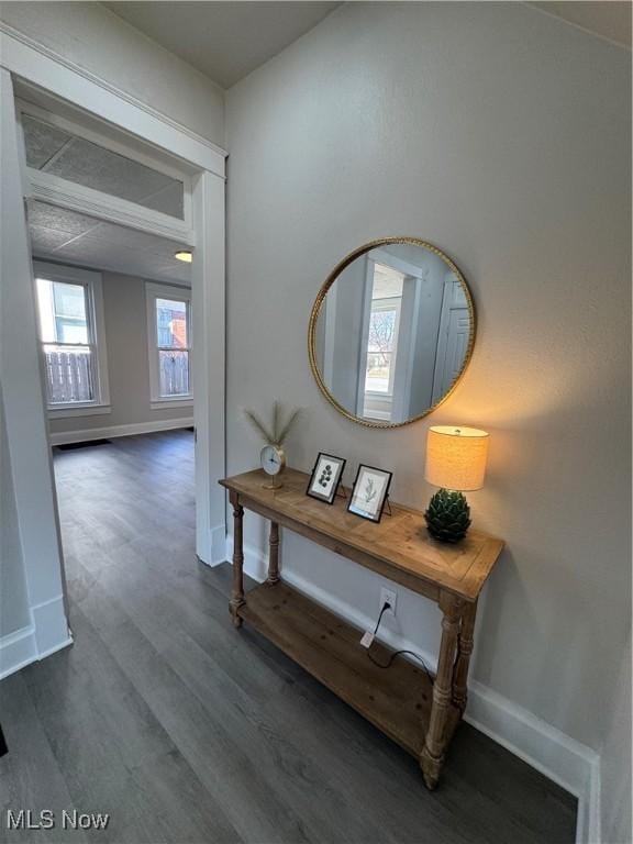 hallway featuring dark wood-type flooring and baseboards