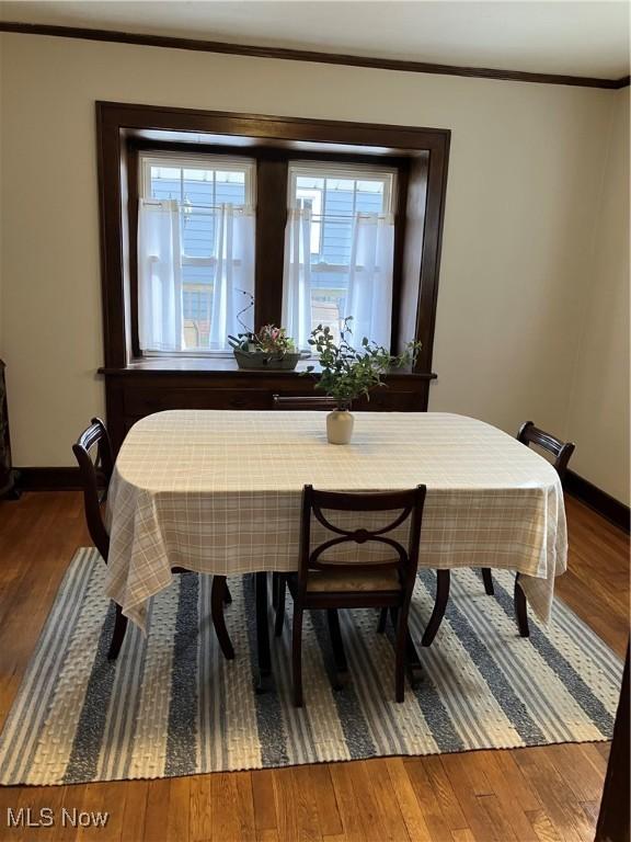 dining space with baseboards, wood-type flooring, and crown molding