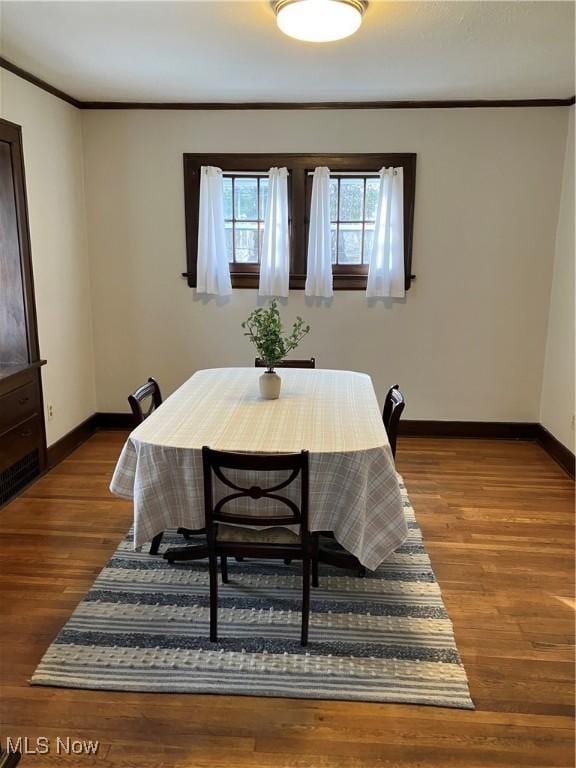 dining area featuring crown molding, baseboards, and wood finished floors