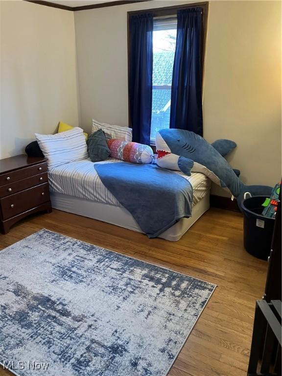 bedroom with wood finished floors and crown molding