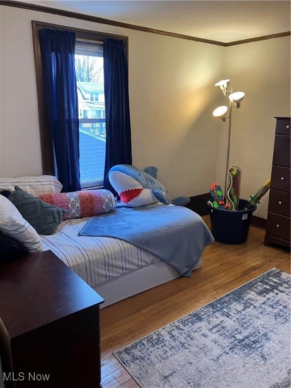 bedroom featuring crown molding and wood finished floors