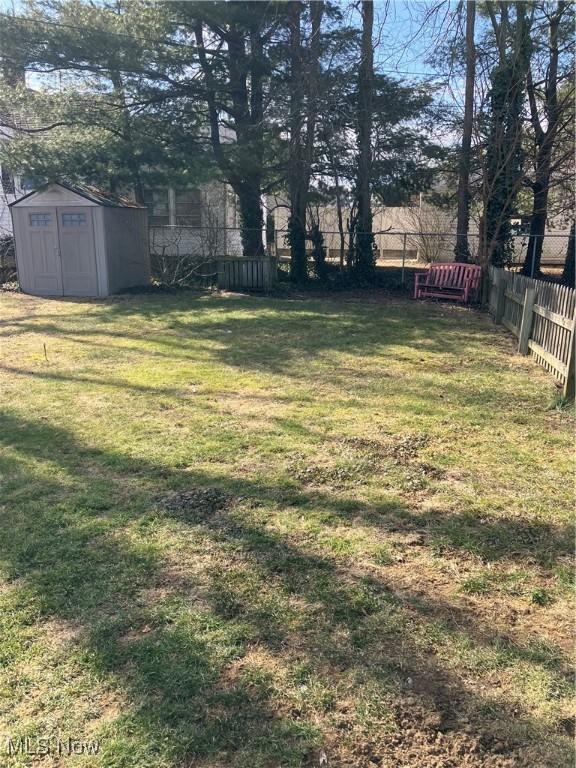 view of yard featuring a shed, fence, and an outbuilding