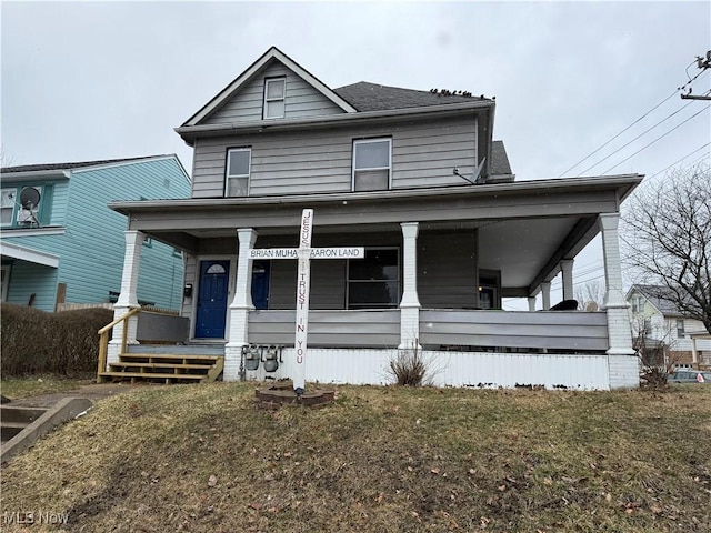 view of front of property featuring a porch, a front yard, and a shingled roof