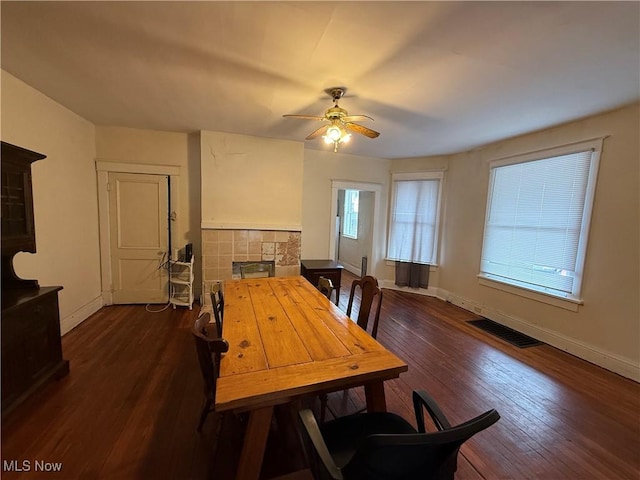 dining space featuring visible vents, baseboards, a fireplace, and dark wood-style flooring