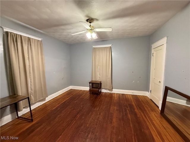 empty room featuring a ceiling fan, wood finished floors, and baseboards