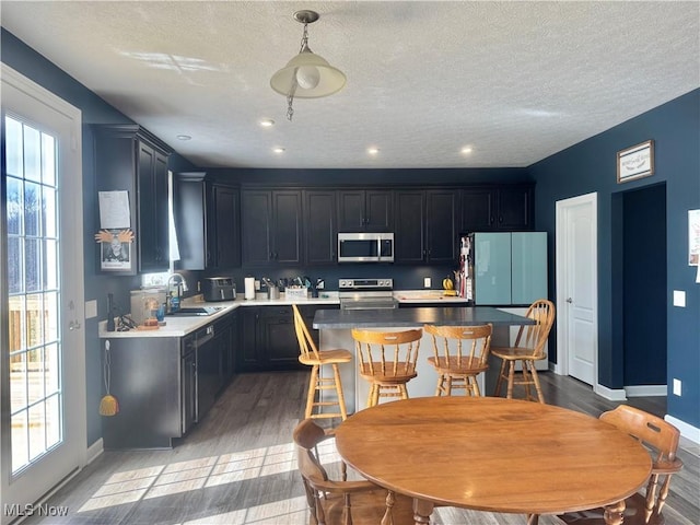 kitchen with appliances with stainless steel finishes, a kitchen island, a sink, and a healthy amount of sunlight