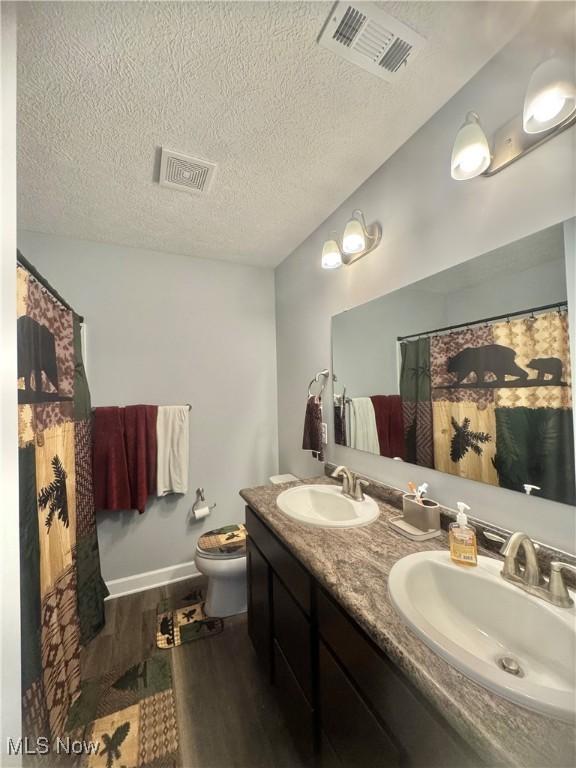 bathroom featuring visible vents, a sink, and wood finished floors