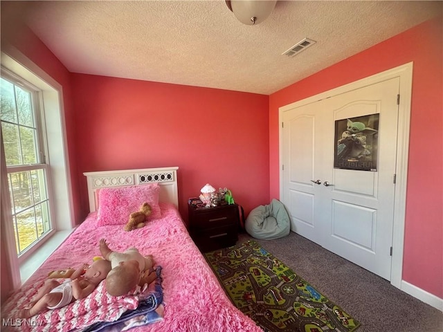 bedroom featuring a textured ceiling, carpet floors, visible vents, and baseboards