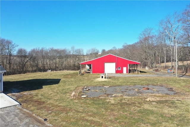 view of yard featuring a garage, a pole building, an outdoor structure, and driveway