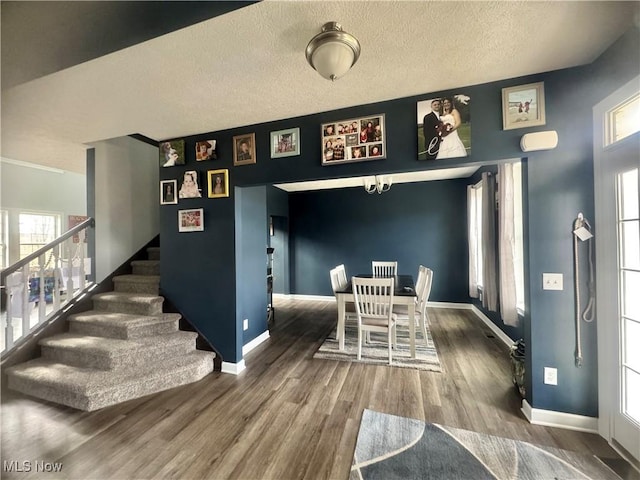 dining room with baseboards, a textured ceiling, stairway, and wood finished floors