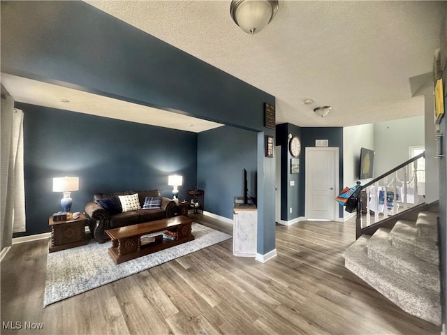 living area with stairs, baseboards, and wood finished floors