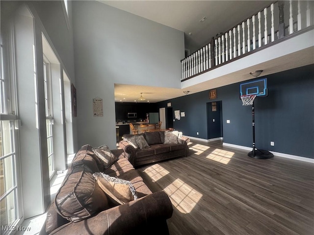 living area featuring wood finished floors, a towering ceiling, and baseboards