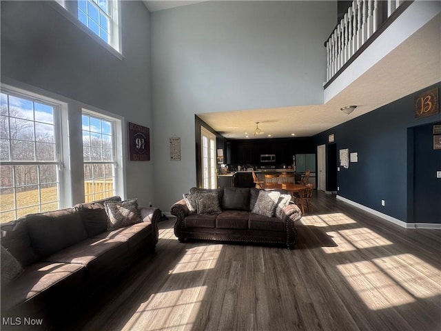 living room with dark wood-style flooring, a healthy amount of sunlight, and baseboards