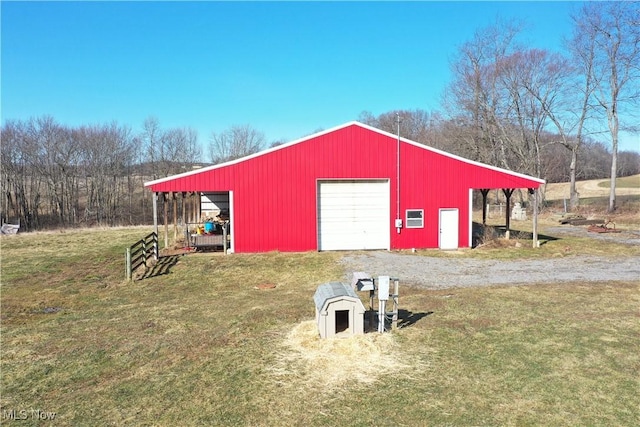 view of pole building with gravel driveway and a yard