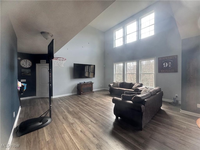 living area with a textured ceiling, wood finished floors, visible vents, and baseboards