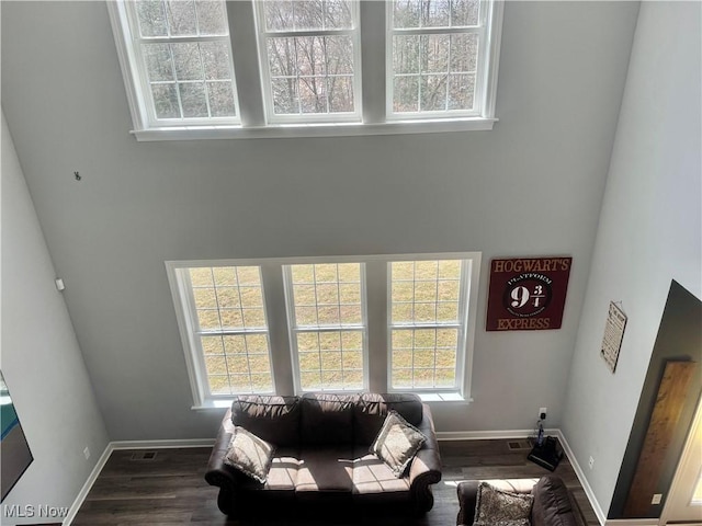 living room featuring baseboards, wood finished floors, and a healthy amount of sunlight