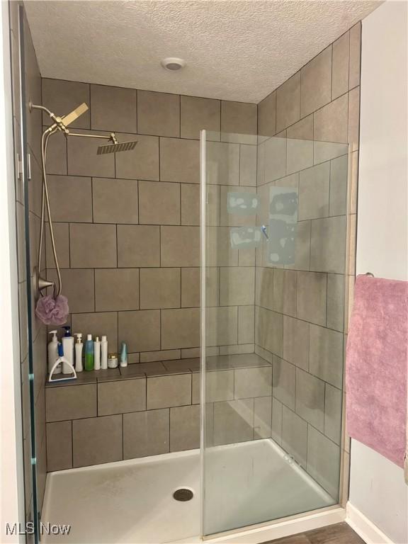 full bathroom featuring a stall shower and a textured ceiling