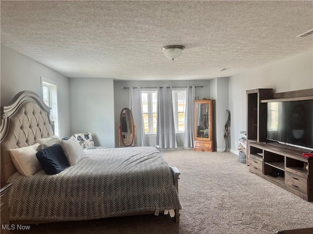 carpeted bedroom with a textured ceiling, visible vents, and baseboards