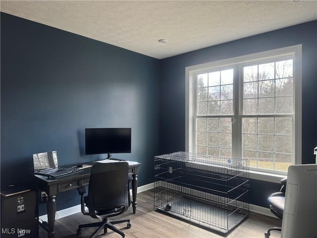 home office with a textured ceiling, baseboards, and wood finished floors