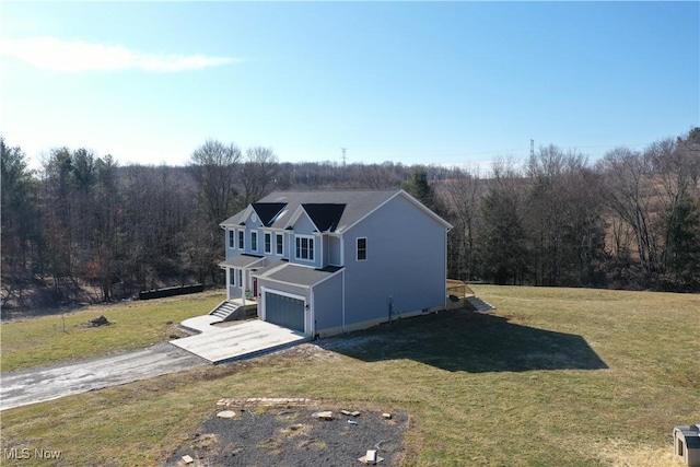 exterior space with driveway, a yard, and a wooded view