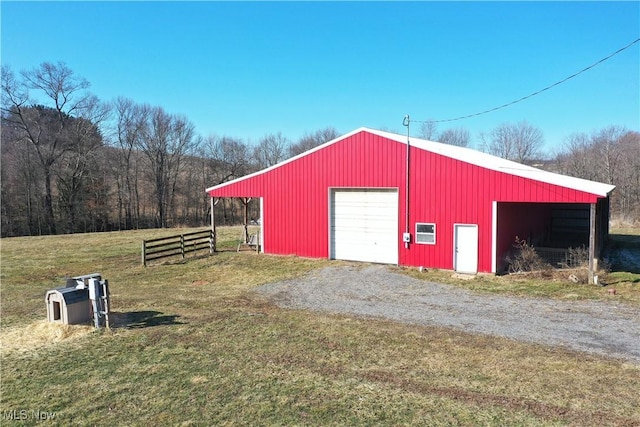 view of pole building with gravel driveway, a yard, and fence