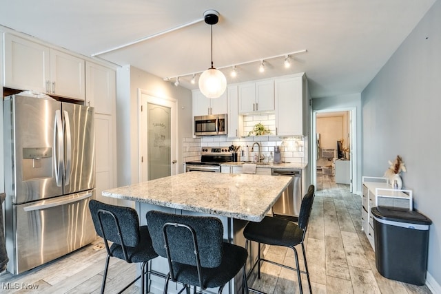 kitchen with white cabinets, stainless steel appliances, decorative backsplash, and wood finish floors