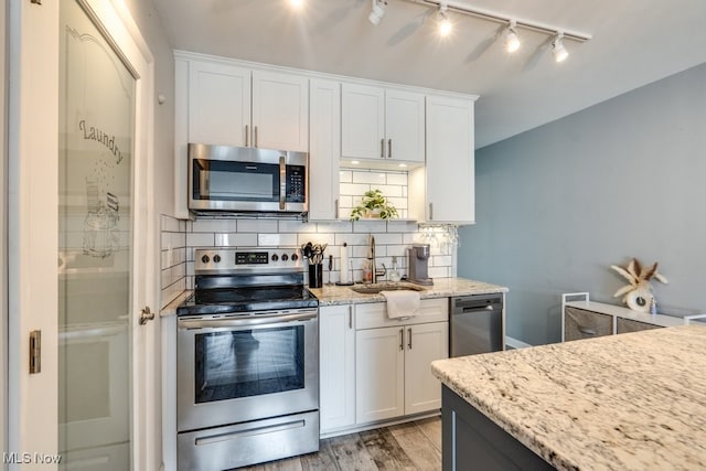 kitchen with white cabinets, appliances with stainless steel finishes, decorative backsplash, and a sink