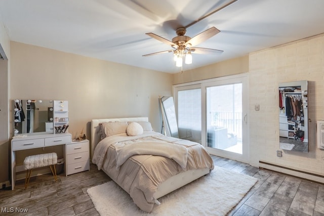 bedroom with access to exterior, a ceiling fan, wood finished floors, and a baseboard heating unit