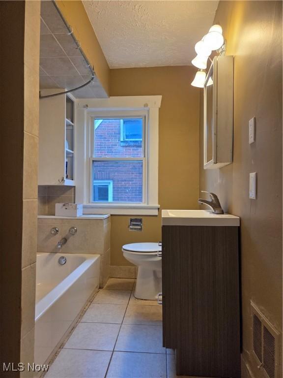 full bathroom featuring a garden tub, toilet, tile patterned flooring, vanity, and visible vents