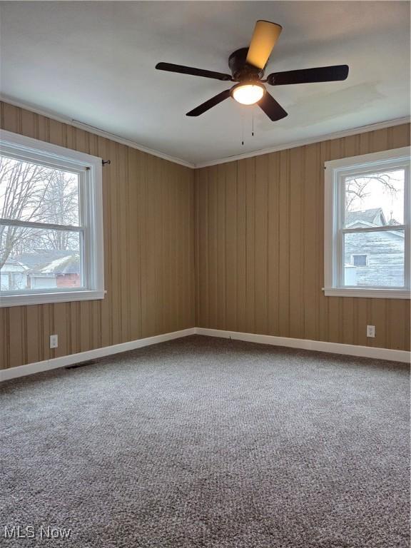 unfurnished room with carpet, visible vents, crown molding, and baseboards