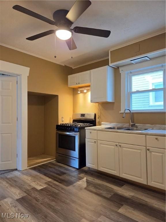 kitchen with stainless steel gas range, white cabinets, crown molding, and a sink